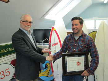 Don Feagan, President and COO of SAi (left), presents Will Mclear, owner of Ocean Graphics & Signs, with a commemorative trophy and plaque